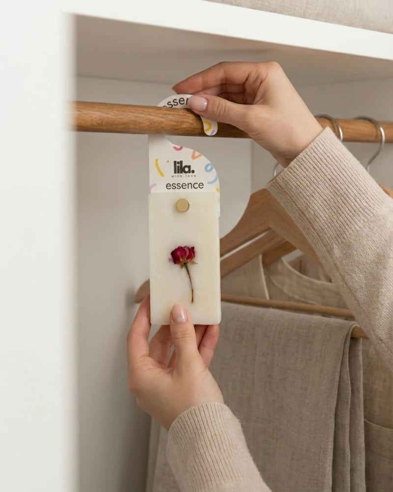 Hand holding a delicately scented wax sachet from Lila with Love, hanging it inside a wardrobe to softly fragrance clothes and small spaces.